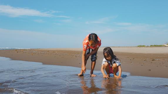 two children, a boy and girl, play on the beach on a sunny summer day