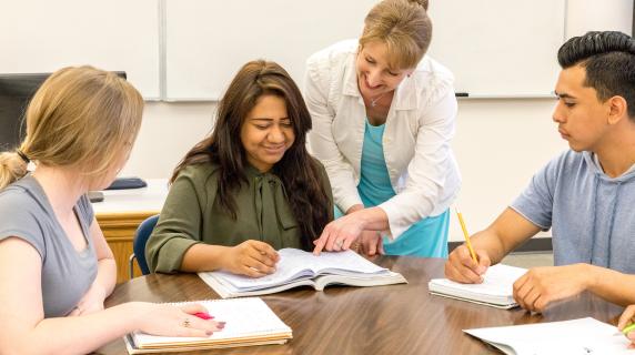 teacher helping group of students on classwork