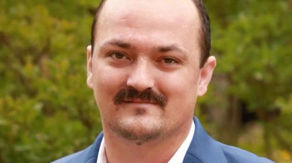 A student in a blazer with a mustache