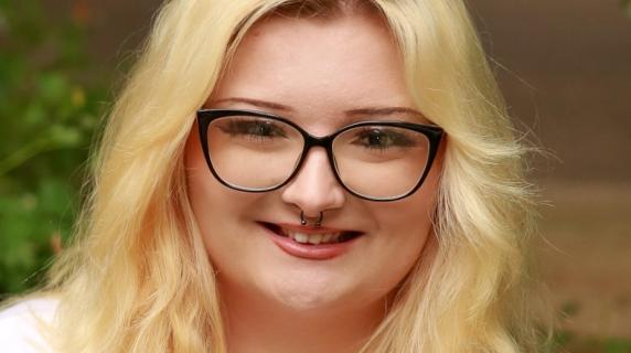 A woman with blond hair and black glasses