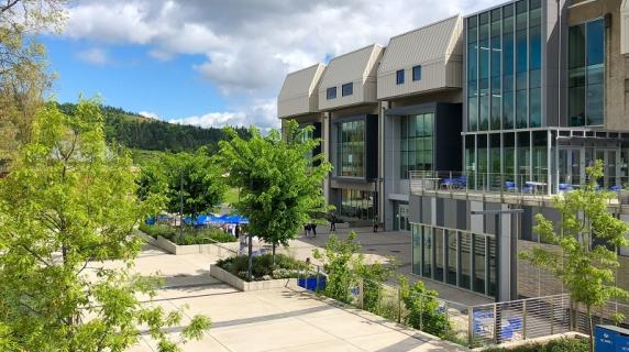 The center building on campus on a sunny day with bright green trees in the foreground
