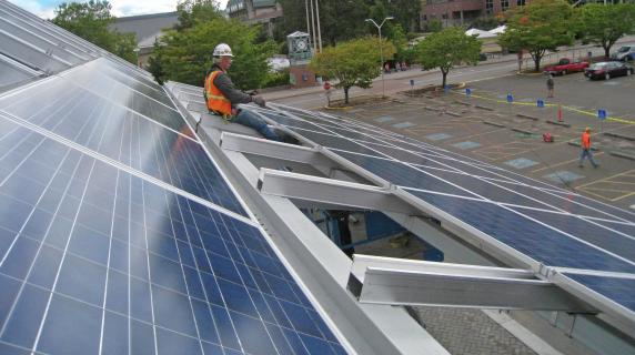person in hardhat and orange vest installing solar panels