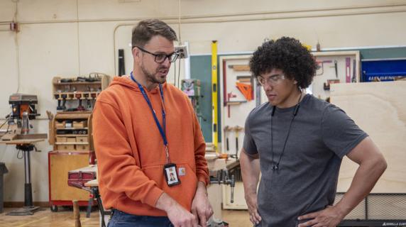 Student speaking with a teacher in a high school classroom
