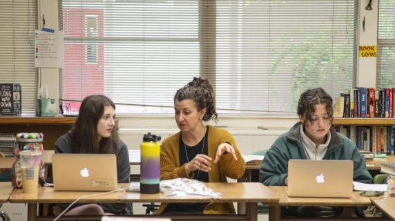 Two high school students speaking with their teacher