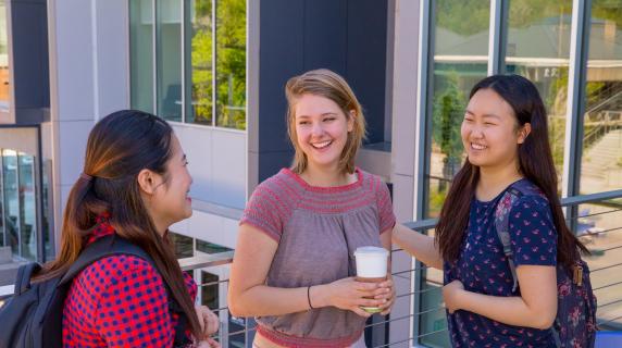 happy students with backpacks and coffee smiling and talking
