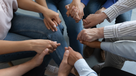 close up of people holding hands in a circle