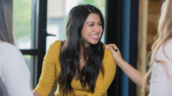 a woman smiling as a friend pats her shoulder