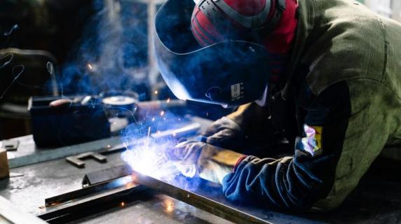 a sheet metal technician with safety gear welding metal