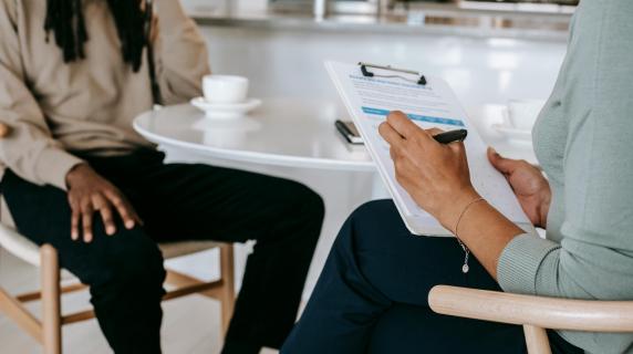 A SHRM certified professional interviews a man at a cafe