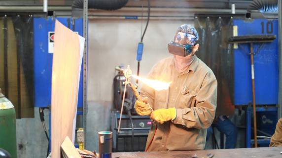 a welding student working in the workshop with a torch