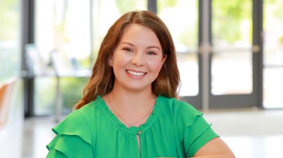 Cheyenne, a red hair student wearing a green shirt, sitting sideways in a chair. 