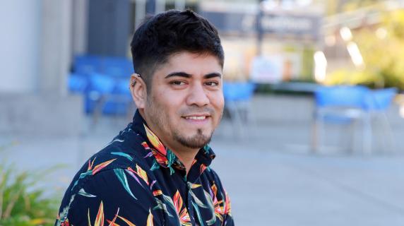 Miguel, a person sitting outside the front of the lane center building in a hawaiian shirt with legs crossed. 
