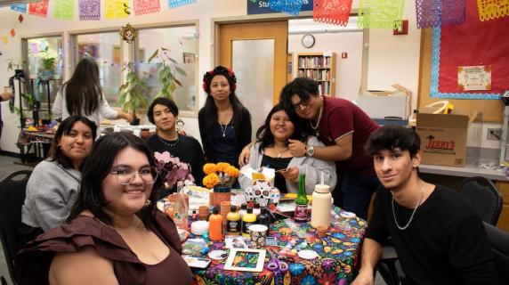 MEChA students at the Multicultural Center smiling and celebrating Dia de los Muertos
