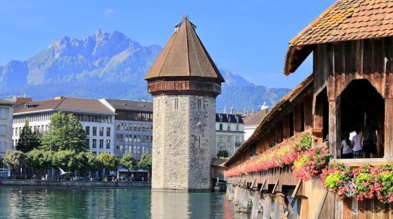a beautiful covered bridge over a lake in Lucerne, Switzerland with mountains in the background 