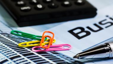 close up of a stack of papers with colorful paperclips, a pen, and a calculator on top