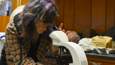 student in geology lab looking through microscope