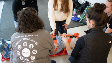 an EMT instructor teaches high school students how to safely put a patient on a stretcher