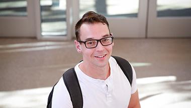 Headshot of Jonathan, wearing a backpack inside a building lobby