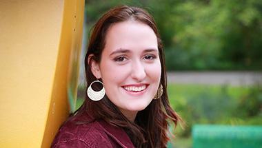 Headshot of Zoe, standing next to a yellow statue on campus