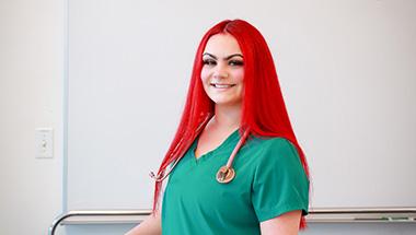 Headshot of Tess, in a nursing uniform with a stethascope around her neck