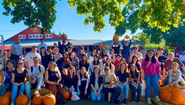 student members of International Christian Fellowship pose with large pumpkins on a farm field trip