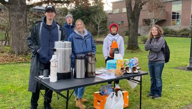 student members of Northwest Collegiate Ministry handing out free hot chocolate at the entrance of campus on a cool fall day