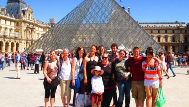 students studying abroad in France posing in front of the glass pyramid at the Louvre
