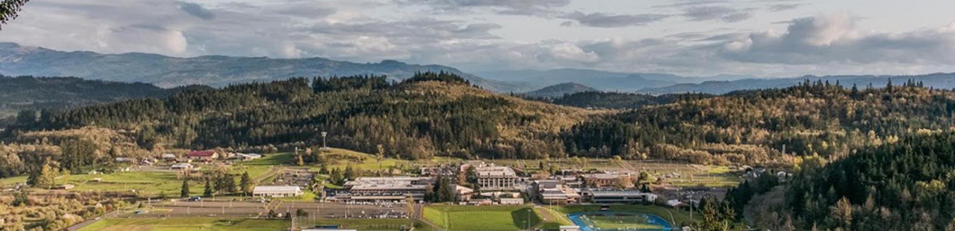 Overview shot of campus, from the hills to the North, showing a landsacpe of green with a distinct blue track