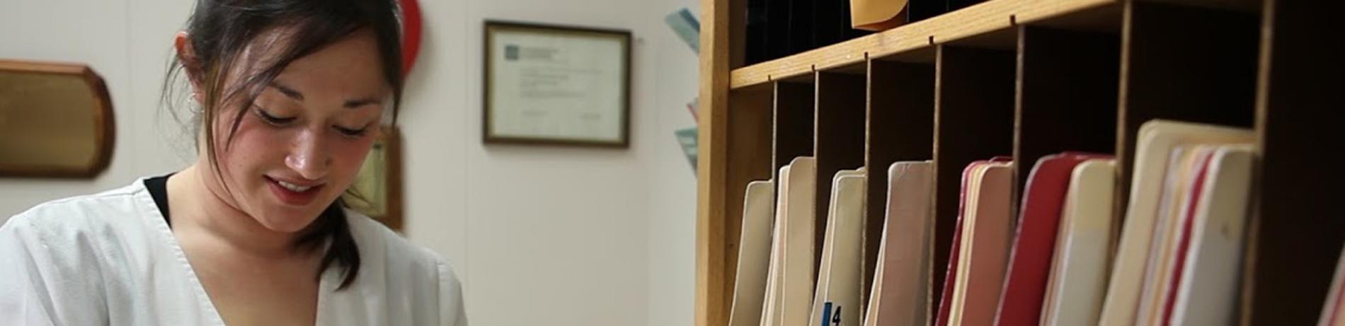 A health information management student, reviewing records in a medical office