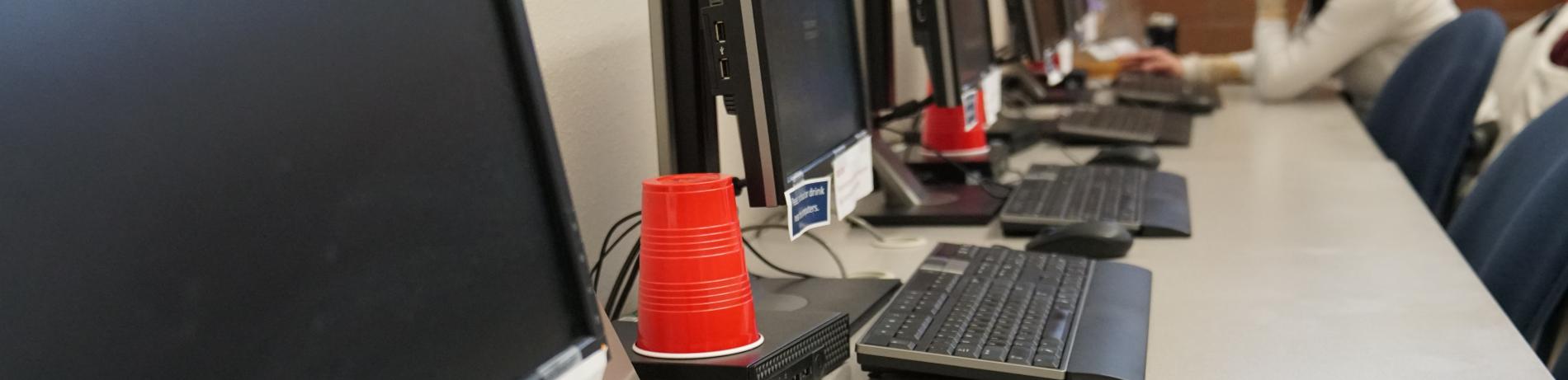 a long table against a wall with a row of PC computers