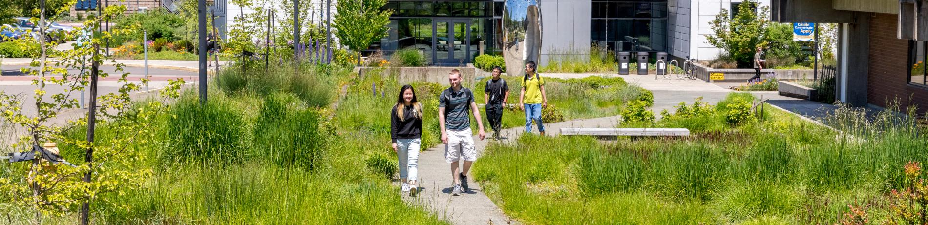 students walking up the path through natural landscaping from the health and wellness building on lane community campus.