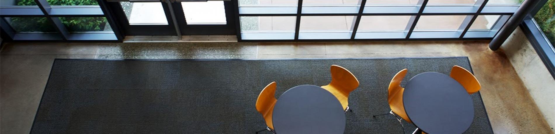 an above view looking down at 2 tables with chairs in front of large windows and glass doors