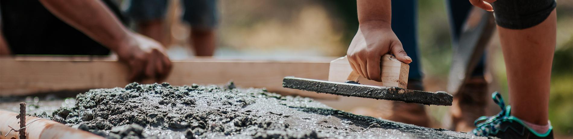 people pouring and smoothing concrete in construction project