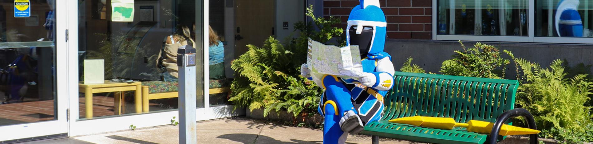 LCC mascot Ty sitting on bench in the sun outside building 1