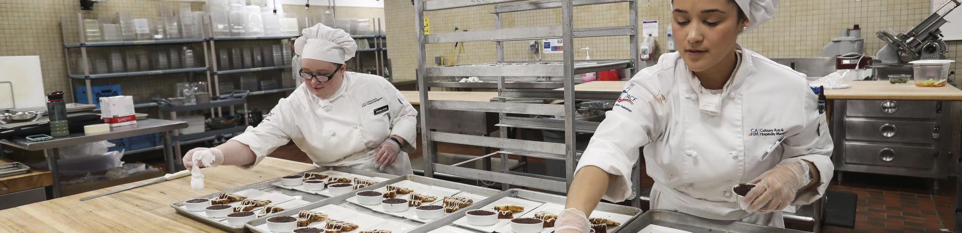 two culinary students arrange desserts in a kitchen