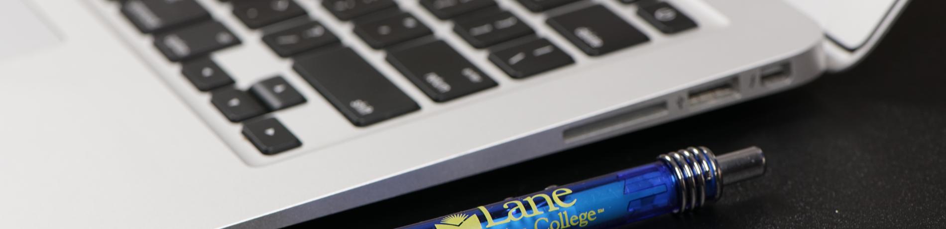 close up of laptop with an lcc-branded pen next to it