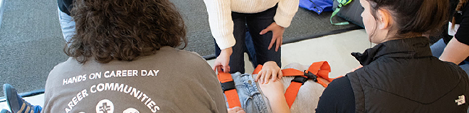 an EMT instructor teaches high school students how to safely put a patient on a stretcher