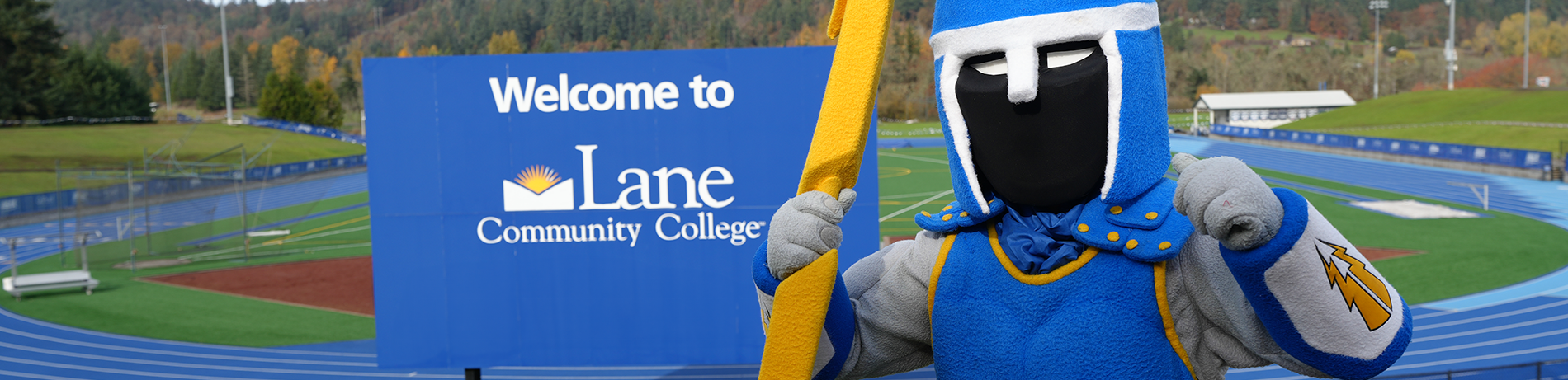 ty the titan mascot posing in front of the LCC sign by the track
