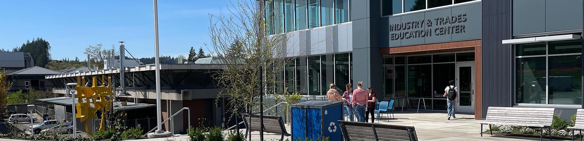 The front entrance of the ITEC building on a sunny spring day with students meeting out front