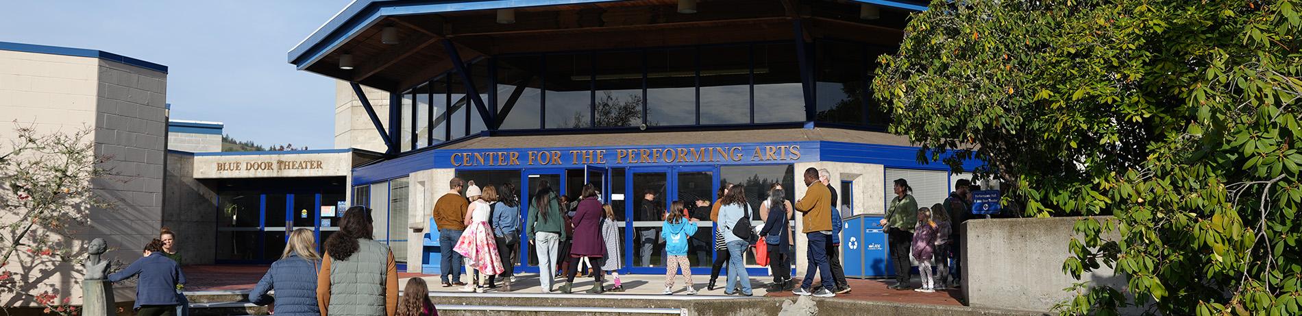 People of all ages arrive for a performance outside the Center for Performing Arts building on a pretty fall day