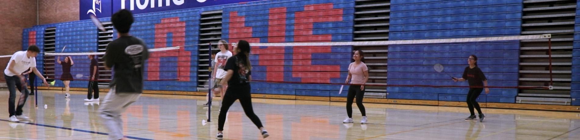Students laugh and play badminton in a PE/Fitness class at the LCC gym
