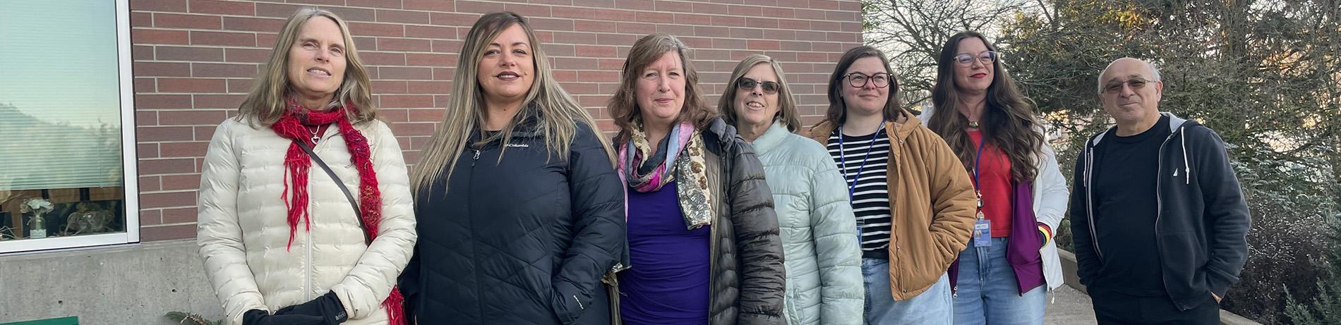 Lane's seven college achievement coaches lined up and smiling outside Building 1 on a sunny winter day