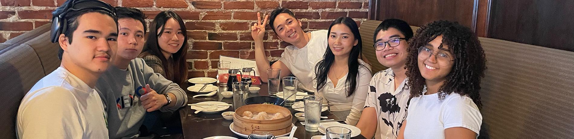 international students smiling and dining at a restaurant together
