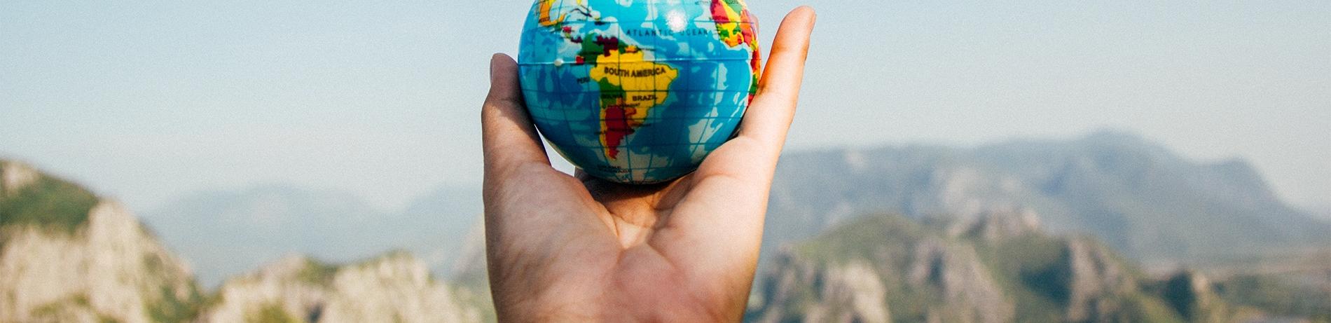 an international student studying in Eugene, Oregon goes on a hike and holds up a small globe