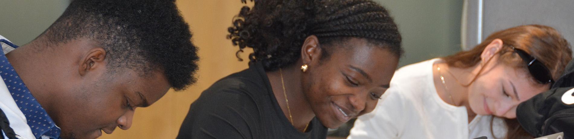 Three LCC students smiling and studying for Writing and Math Course Placement in Haugland Commons