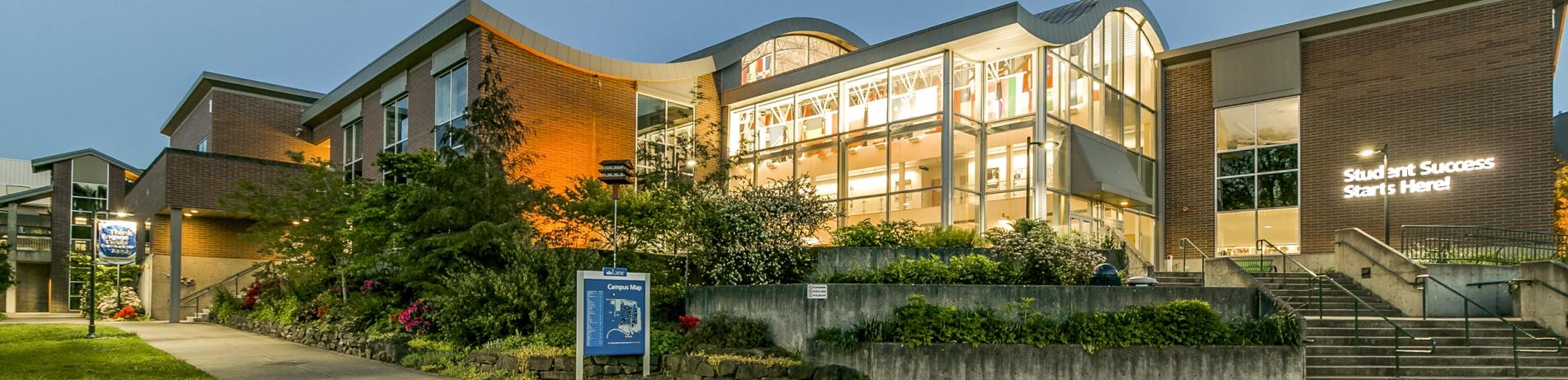 Building 1 lit up at dusk with the words "student success start here" illuminated on the side