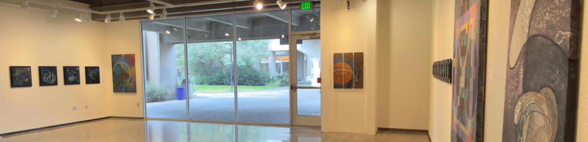 view of Roger Hall gallery with colorful abstract oil paintings installed on white gallery walls