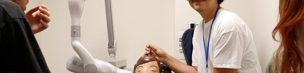 a teenage boy at a health professions summer camp smiles and poses with a dental hygiene dummy