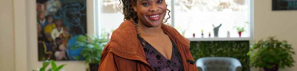 a young black woman with long braided hair and a poofy jacket in the Multicultural Center