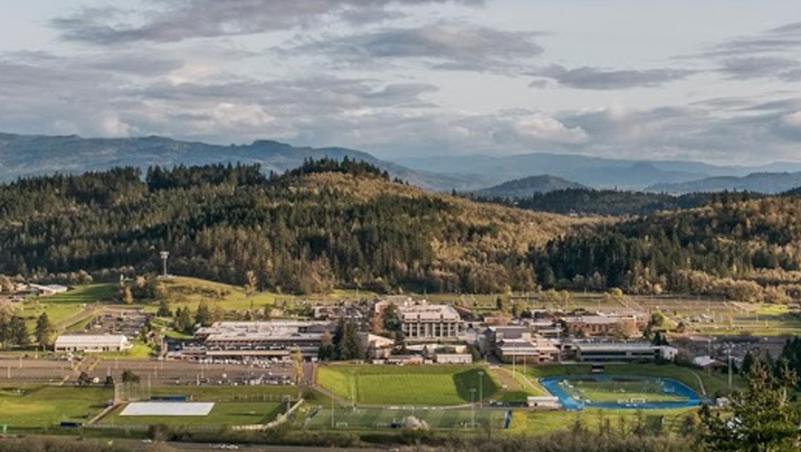 Overview shot of campus, from the hills to the North, showing a landsacpe of green with a distinct blue track